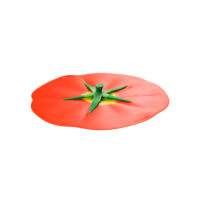 A Charles Viancin tomato-shaped silicone lid cover in red with a green stem and small yellow accent, shown on a plain white background.