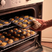 De Buyer Muffin trays filled with cooked savoury muffins being taken out of the oven.