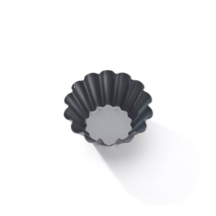 A dark gray fluted tart tin or cup with a scalloped rim, shown from a top-down perspective on a clean white background.