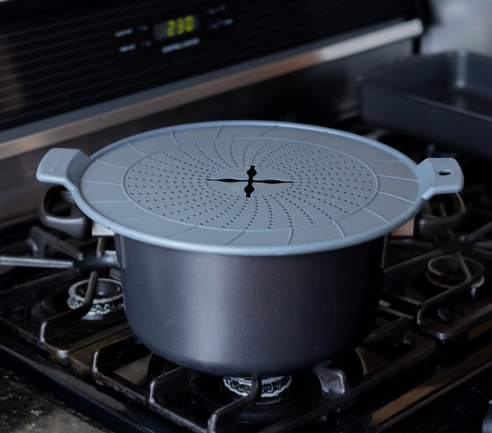 SCANPAN 24–32cm splatter guard protecting a saucepan from cooking splashes