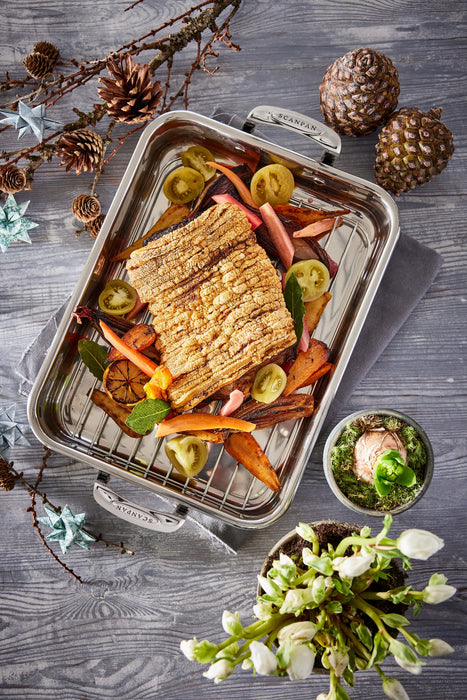 Grilled fish with vegetables on a Scanpan STS Roasting Rack, surrounded by decorative elements on a wooden surface.