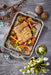 Grilled fish with vegetables on a Scanpan STS Roasting Rack, surrounded by decorative elements on a wooden surface.